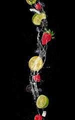 Wall Mural - Pieces of fruit in water splash, isolated on black background