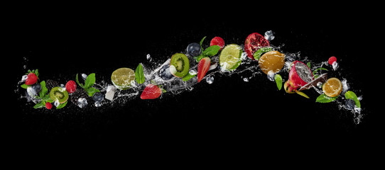 Wall Mural - Pieces of fruit in water splash, isolated on black background