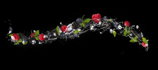 Fototapete - Mix of berry fruit in water splash, isolated on black background