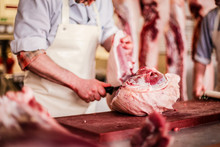 Butcher Cut Raw Meat Of A Pig With A Knife At Table In The Slaughterhouse