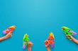 Hands holding plastic water gun on blue background