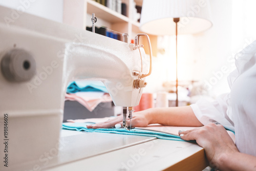 dressmaker in sew studio working on sewing machine woman seamstress