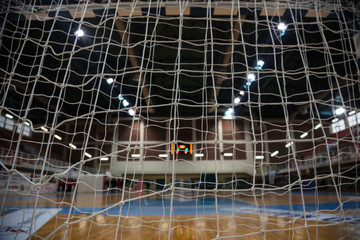 Wall Mural - Handball concept. Goal post nets from behind view. Blurred court, athletes and electronic scoreboard background.