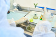 © Seventyfour - Close-up of unrecognizable environmental scientist in protective gloves holding plant leaves with tweezers while analyzing sample in isolation workstation
