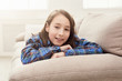 © Prostock-studio - Happy little girl lying on sofa at home