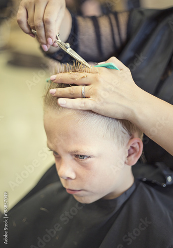 A Cute Young Blonde Boy Getting His Hair Cut At A Beauty Salon Or