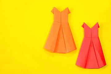 Bright colored origami women's dress on a yellow background.