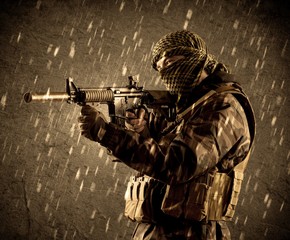 Portrait of dangerous heavily armed terrorist soldier with mask on grungy rainy background