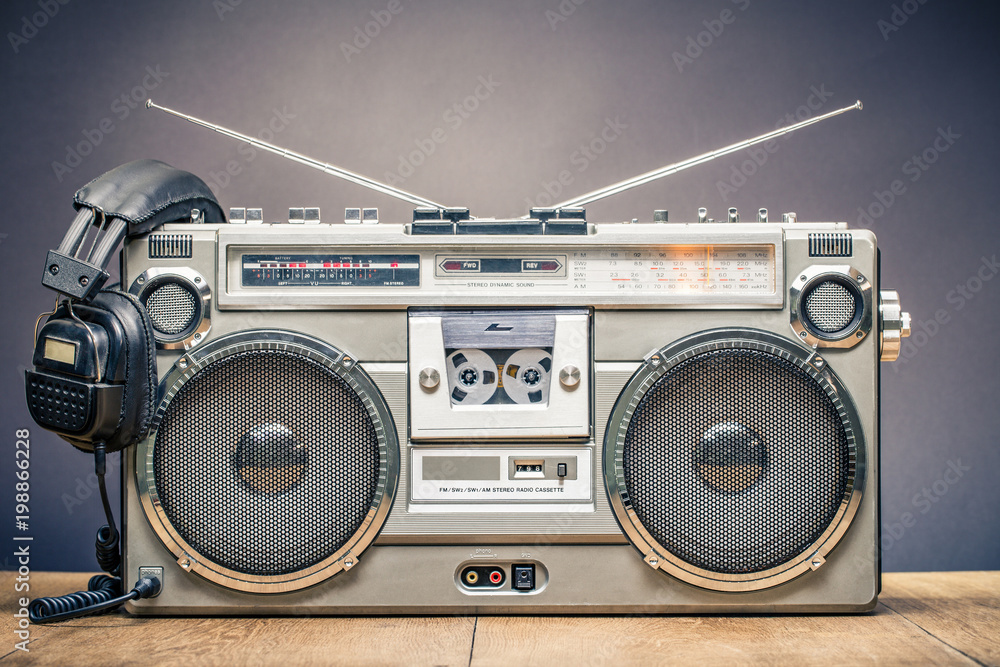 Retro outdated portable stereo boombox radio cassette recorder from circa late 70s with aged headphones front gradient black wall background. Listening music concept. Vintage old style filtered photo - obrazy, fototapety, plakaty 