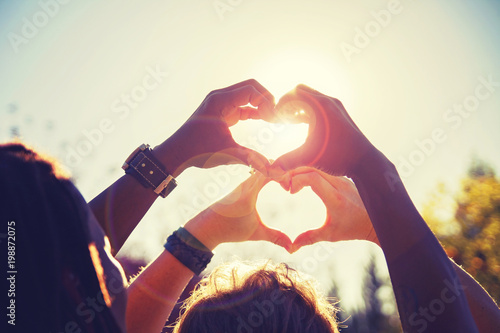 Fotomural beautiful photo of a couple making heart shapes with their hands toned with a re