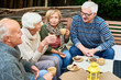 © Seventyfour - Group portrait of three senior people chatting happily telling stories meeting for lunch  on outdoor terrace