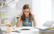 © New Africa - Teenage girl suffering from headache while doing homework at table indoors