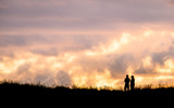 Fototapeta Kosmos - Silhouette scene of a couple enjoy with their drone at sunset on the top of Mt. Eden, Auckland, New Zealand.