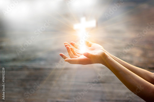 Photographie Woman with white cross in hands praying for blessing from god on sunlight backgr