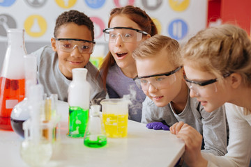 fond of chemistry. the group of upbeat teenage students being gathered around the table in their sch