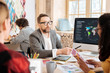 © Viacheslav Yakobchuk - Our success. Handsome serious bearded man talking with his colleagues and showing information of the screen while sitting at the table