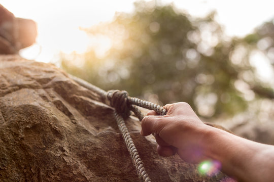 men climbing on rock outdoor, close-up image of climber hand