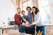 © Viacheslav Yakobchuk - We are team. Good-looking alert young employees smiling and holding hands while being in the office
