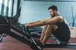 © LIGHTFIELD STUDIOS - Side view of sportsman doing exercise on rowing machine in sports center