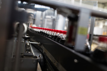 Wall Mural - Bottling factory - Black juice or soft drink bottling line for processing and bottling juice into bottles. Selective focus.