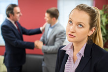 Unhappy Businesswoman With Male Colleague Being Congratulated