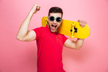 Wall Mural - Portrait of a joyful young man in sunglasses celebrating