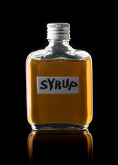 Wall Mural - glass bottle of syrup on black background.