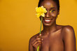 © Mike Orlov - Cheerful young african woman with yellow makeup on her eyes. Female model laughing against yellow background with yellow flower.