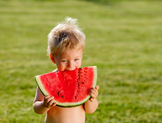 Wall Mural - One year old baby boy eating watermelon in the garden