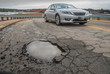 Non descript car steering clear of big pothole