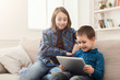 © Prostock-studio - Two kids with gadgets on couch at home