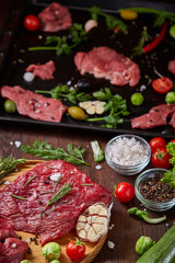 Wall Mural - Still life of raw beef meat with vegetables on wooden plate over vintage background, top view, selective focus