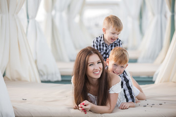 Wall Mural - Summer portrait of mother and two son on the beach. Happy family