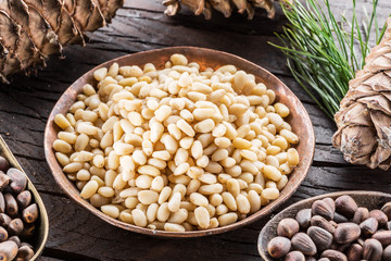 Wall Mural - Pine nuts in the bowl and pine nut cones on the wooden table. Organic food. Top view.