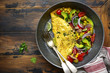 Omelette stuffed with vegetables in a black skillet for a breakfast.Top view with copy space.