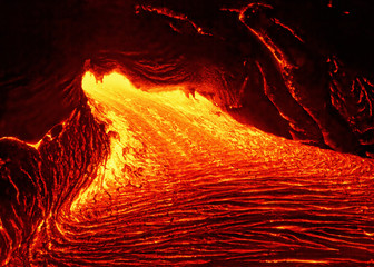 scenic view of a part of a lava flow in the dark, the hot lava shows up in yellow and red shades - l