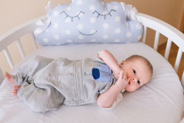 beautiful newborn baby lying in an round bed with beautiful bumpers in delicate gray, blue, white to