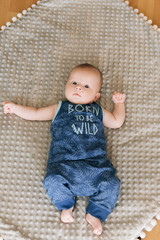 Handsome fashionable little boy lying on a blanket, with a sweet expression