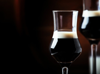 Two-layer cocktail with coffee liqueur, vintage wood background, selective focus