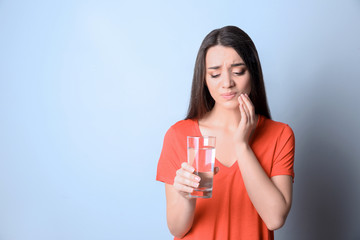 Canvas Print - Woman with sensitive teeth holding glass of water on color background