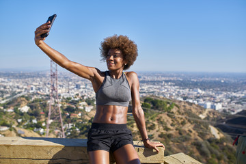 fit african american woman taking selfies at runyon canyon with los angeles in background