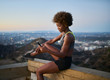 © Joshua Resnick - athletic african american woman using smartphone at runyon canyon while resting on bench at dusk