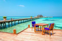 Tables And Chairs In A Wooden Restaurant On Stilts On The Background Of Azure Water And Blue Sky