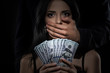 A frightened woman holds a pack of dollars. The man closes the woman's mouth with his hand. Corruption