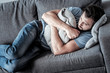 Absolute solitude. Top view of a depressed unhappy sad man lying on the sofa and hugging a cushion while feeling lonely