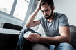 © Viacheslav Yakobchuk - My medication. Sad unhappy bearded man touching his forehead and looking at the pills while sitting on the sofa