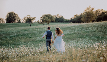 Wall Mural - Beautiful bride and groom at sunset in green nature.