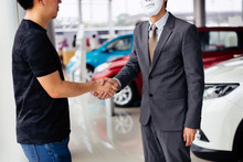 Dishonest And Evil Salesman In Business Suit In Car Dealership Company Handshaking Welcome Customers To Exploit And Deceive Customers - Fraud And Bad Quality Service In Business Concept.