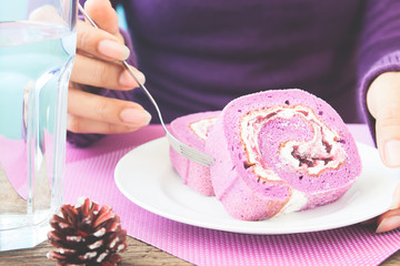 Wall Mural - Woman in purple knit clothing eating blueberry roll cake, Purple color tone