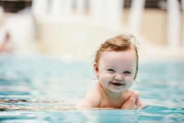 Baby girl smiling and swimming in water.